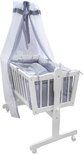 Wit houten kinderbed met blauwe ruitjesbekleding en hemel met strikken.