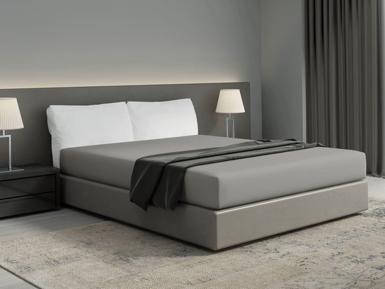 Un lit double avec linge de lit gris, draps gris foncé et coussins décoratifs.