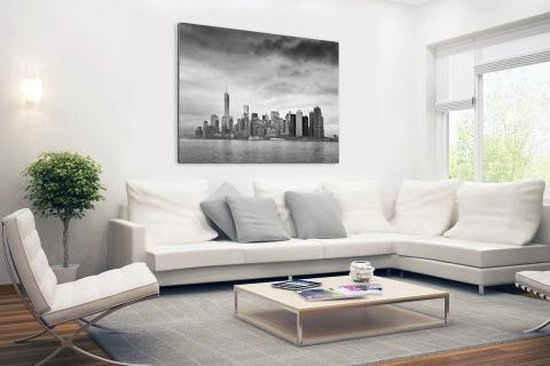 Photo noir et blanc de la skyline de Manhattan, dans un salon moderne avec un canapé d'angle blanc.