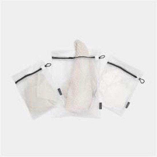 Drie witte gaaswaszakjes, elk met een zwarte rits, met daarin kledingstukken.