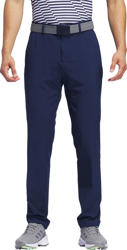 Man met donkerblauwe golfbroek, gestreepte polo en grijze golfschoenen.