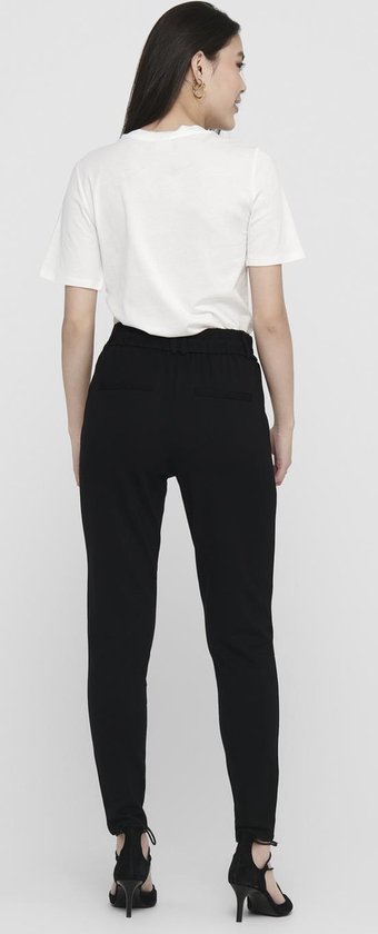 Zicht op de achterkant van een zwarte broek met ceintuur en hoge hakken.