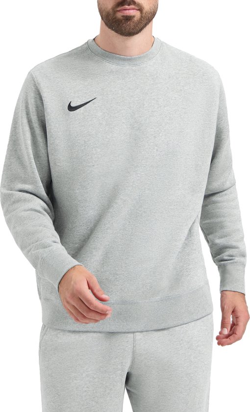 Man met baard draagt een grijze Nike sweater met zwarte swoosh en grijze joggingbroek.