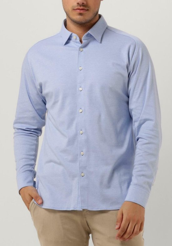 Homme portant une chemise bleu clair à manches longues et un pantalon beige.