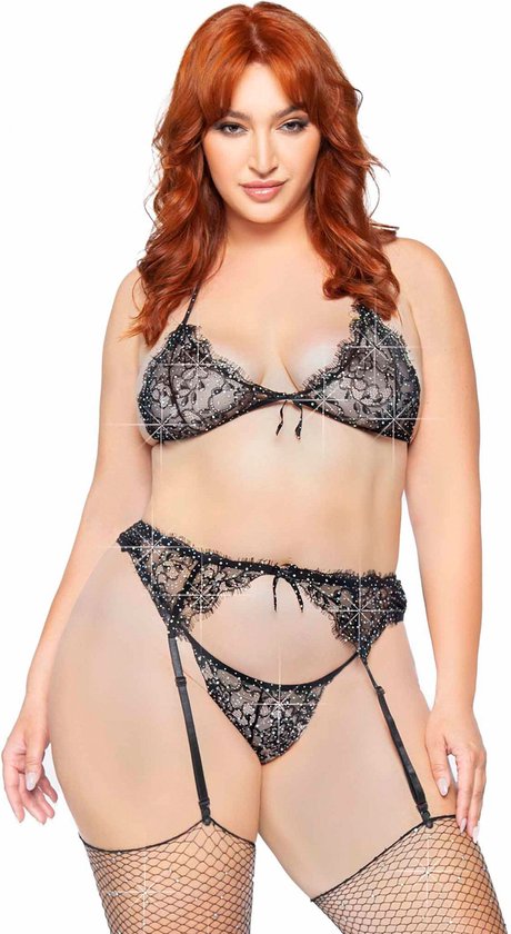 Model met rode haren draagt een zwarte kanten beha met strass, een bijpassende string en jarretel, met visnetkousen.