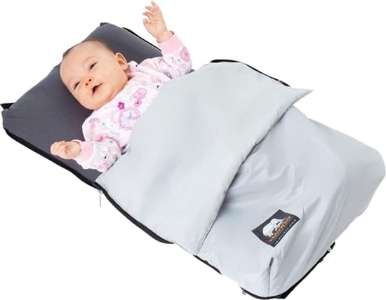 Baby in een grijs reiswieg met een lichte deken en een bloemenprint, op een witte achtergrond.