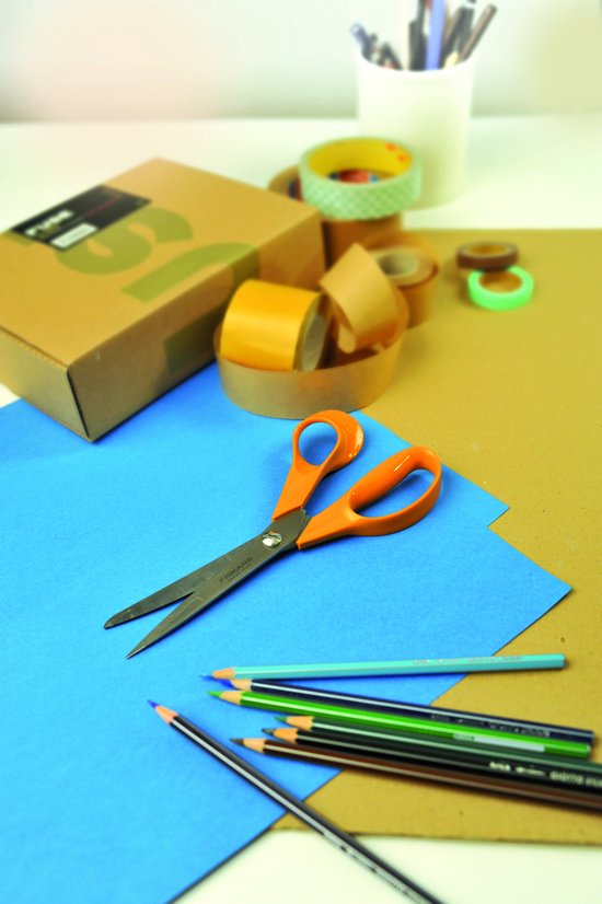 Oranje Fiskars schaar op een blauw vel papier, omringd door gekleurde potloden.