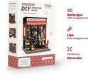 Doos van een miniatuurhuisje 'Uncle Joe's Pizzeria' met informatie over batterijen en lijm.