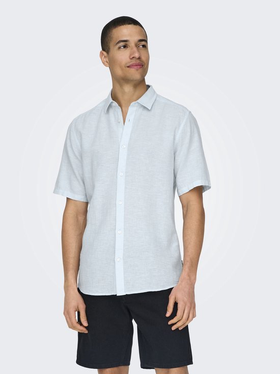 Man die een lichtblauw kortgerokt overhemd draagt, met zwarte shorts.