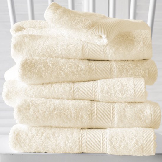 Pile de serviettes en tissu éponge crème avec une subtile texture côtelée horizontale sur le dessus de chaque serviette.