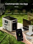 Zilveren AFERIY powerstation op een picknicktafel, bediend via smartphone app, naast een laptop en waterkoker.