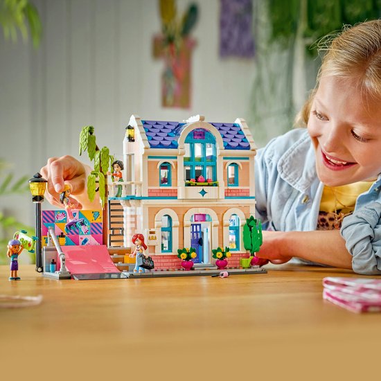 Meisje speelt met LEGO Friends Liann's Familiehuis, met roze dak en blauwe ramen.