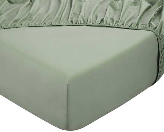 Un drap-housse vert sauge avec élastique, visible sur le coin d'un matelas.