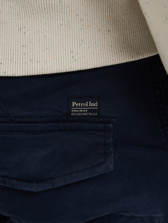 Close-up van het Petrol Industries label op de donkerblauwe cargobroek.