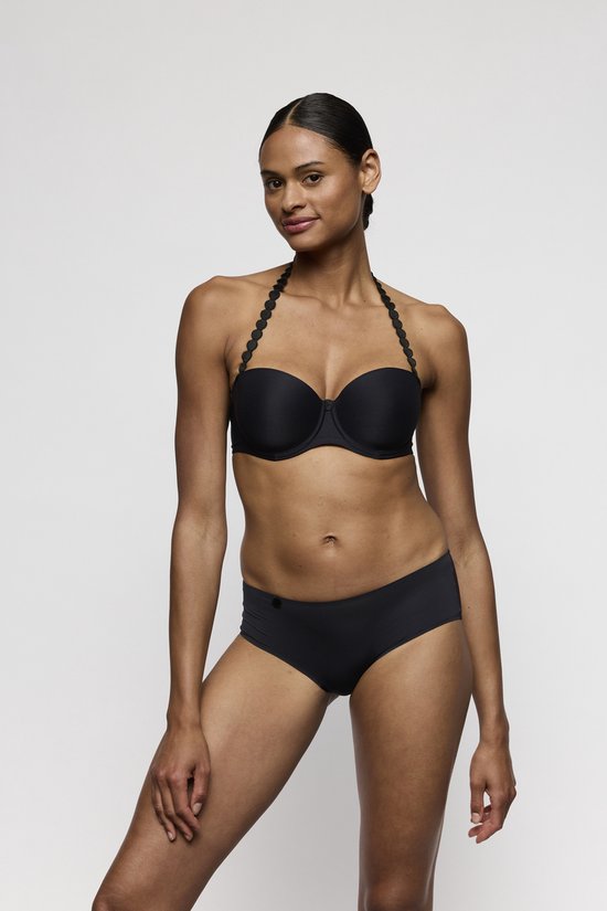 Model met zwarte strapless bh met decoratieve bandjes en bijpassende slip, van opzij gezien.