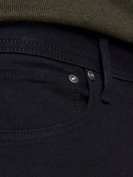 Detail van de voorzak van de zwarte jeans met twee klinknagels.