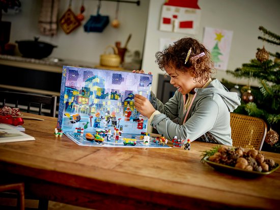 Lachend kind opent een LEGO City Adventskalender met kersttafereel en vele kleine LEGO-bouwwerken.