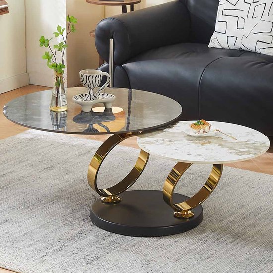 Draaiende salontafel met marmerlook bladen, zwart en wit met goud, met gouden ringen, in een woonkamer.