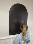 Une fille en sweat à capuche écrit des calculs sur un tableau noir.