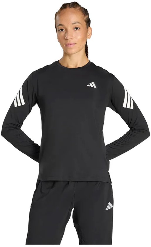 Model draagt een zwart Adidas-shirt met lange mouwen, witte strepen op de armen en een wit logo op de borst.