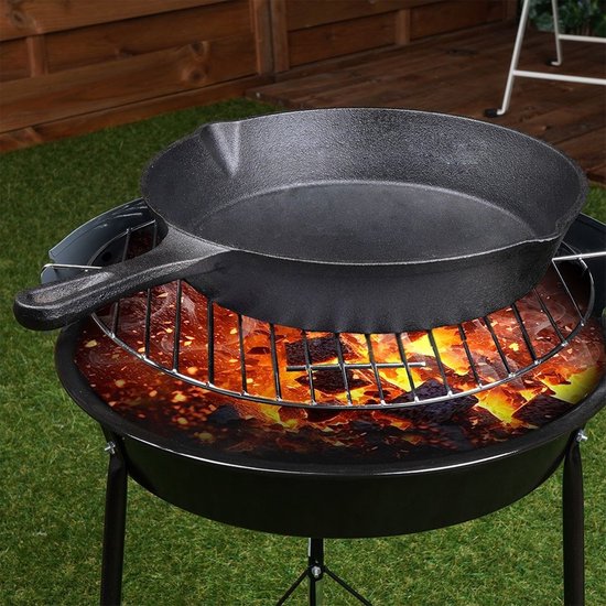 Zwarte gietijzeren koekenpan boven een gloeiende barbecue.