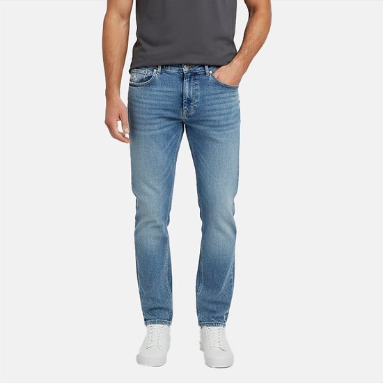 Mannequin portant un jean bleu délavé clair avec des baskets blanches. Le jean a une fermeture boutonnée.