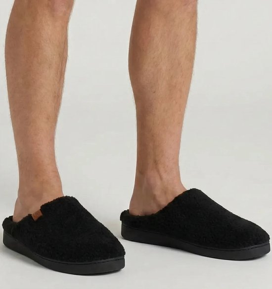 Zwarte teddy wollen herenpantoffels gedragen door een man.
