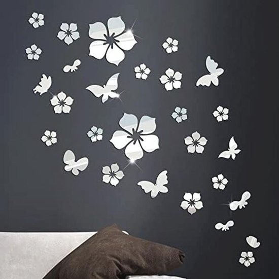 Fleurs et papillons argentés en acrylique sur un mur sombre.
