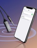 Zilverkleurige Ugreen Bluetooth adapter naast een iPhone.