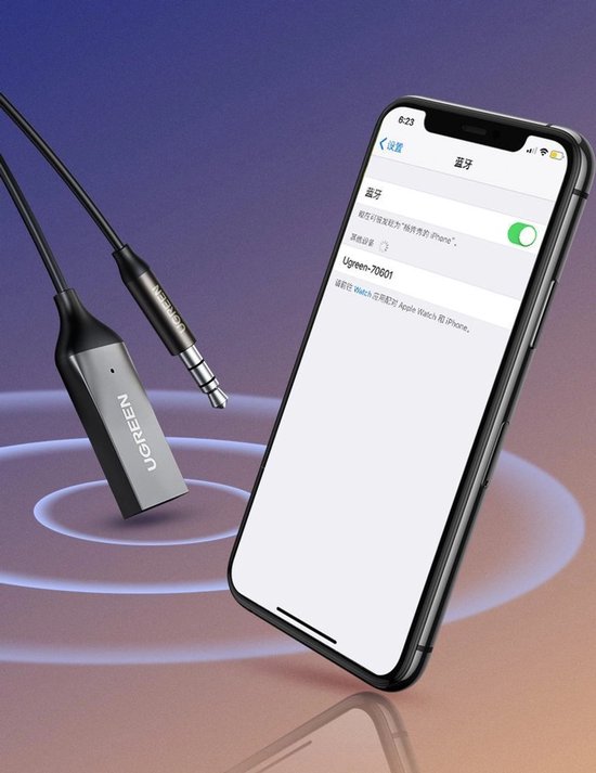 Zilverkleurige Ugreen Bluetooth adapter naast een iPhone.