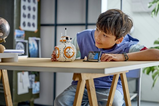 Un garçon regarde un BB-8 LEGO avec un côté qui s'ouvre et un présentoir.