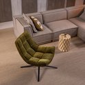 Olijfgroene fauteuil in een woonkamer, naast een beige hoekbank.
