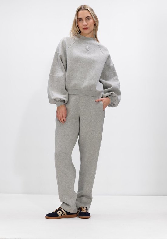 Model in een grijze joggingbroek en bijpassende trui met ballonmouwen.