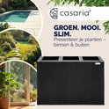 Zwarte plantenbak in polyrotan-look op een terras, naast een zwembad en tuinpad. Tekst: "GROEN. MOOI. SLIM. Presenteer je planten - binnen & buiten."