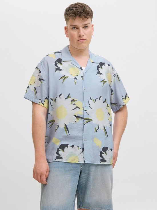 Model in lichtblauw kort hemd met bloemenprint en jeans.