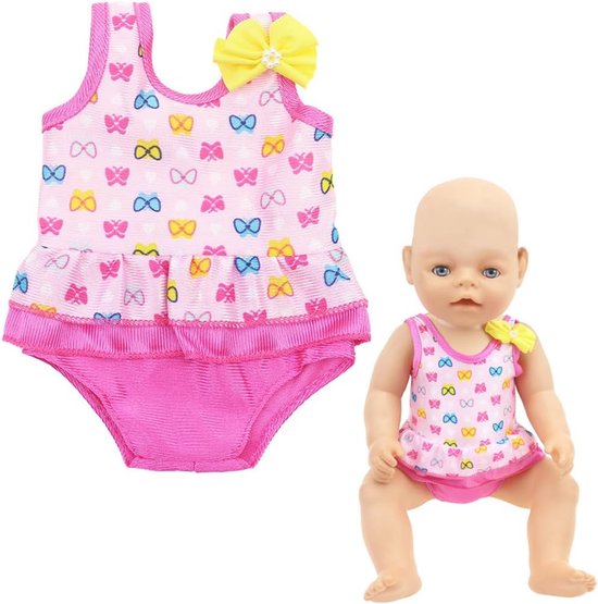 Roze badpakje voor poppen met gekleurde strikjes en een geel strikje, naast een pop die het draagt.