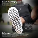Voetzool van een witte gripsok met cirkelvormige antislip noppen.