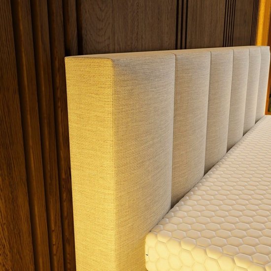Een close-up van het gestreepte beige hoofdbord van de boxspring.