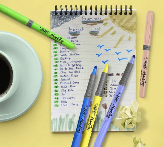 Een notitieboek met een zomer bucketlist, omringd door pastelkleurige BIC markeerstiften, een kopje koffie en een groene BIC markeerstift.