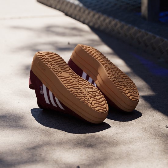 Bordeauxrode sneakers met gum-kleurige zolen en witte Adidas strepen.
