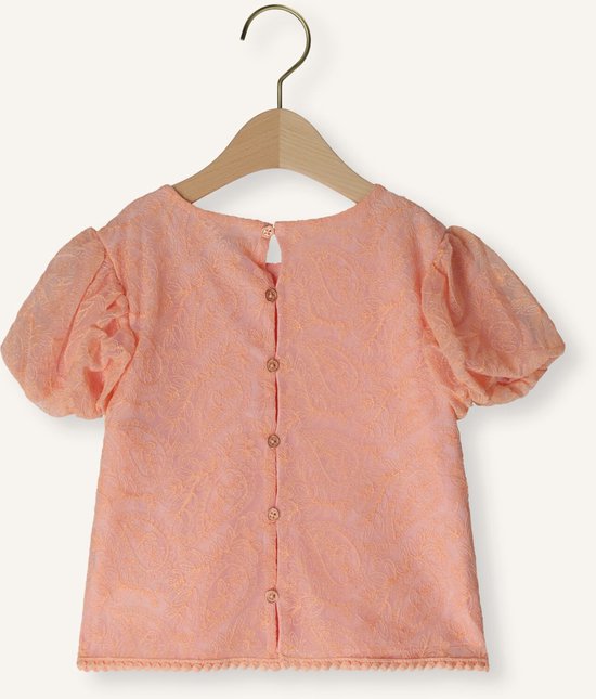 Achterkant van een perzikkleurige blouse met kanten textuur, korte pofmouwen en knoopsluiting.
