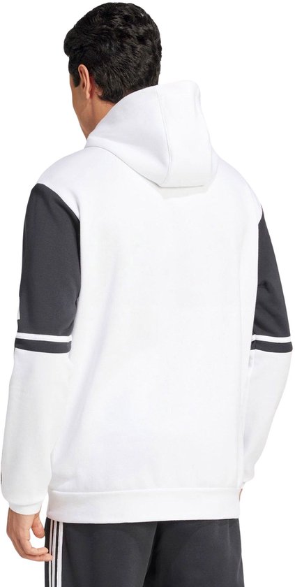 Man met een wit sweatshirt met donkergrijze mouwen en Adidas-strepen op de mouwen.
