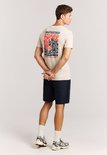 Man met zandkleurig t-shirt met grafische opdruk op de rug.