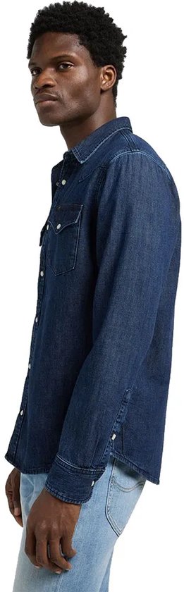 Man in een blauw denim spijkerjack, gezien vanaf de zijkant.