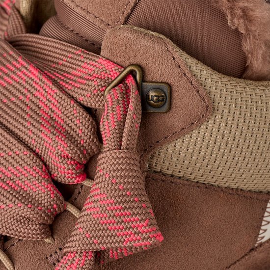 Detail van bruine UGG sneaker: roze geruite veter, metalen veterhaak met UGG logo.