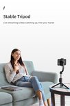 Een vrouw zit op een bank en streamt live, met een telefoon op een stabiele selfie-stick-statief op een salontafel.