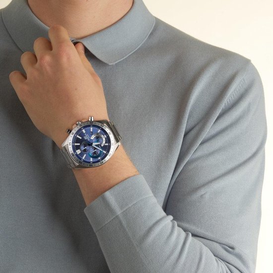 Herenhorloge met zilverkleurige metalen band en blauwe wijzerplaat. Gedragen door een model in een grijs poloshirt.