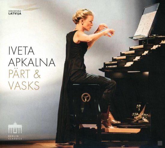 Vrouw speelt op orgel, zittend op kruk, met bladmuziek. Tekst: IVETA APKALNA PÄRT &amp; VASKS.