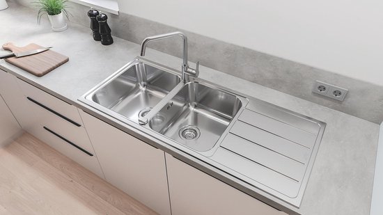 Hoogbouw RVS-look keukenkraan boven een dubbele spoelbak in een lichte keuken.