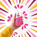 Hand met gele trui houdt een flesje fuchsia Rit Dye vast, tegen een witte achtergrond met roze, gele en paarse patronen.